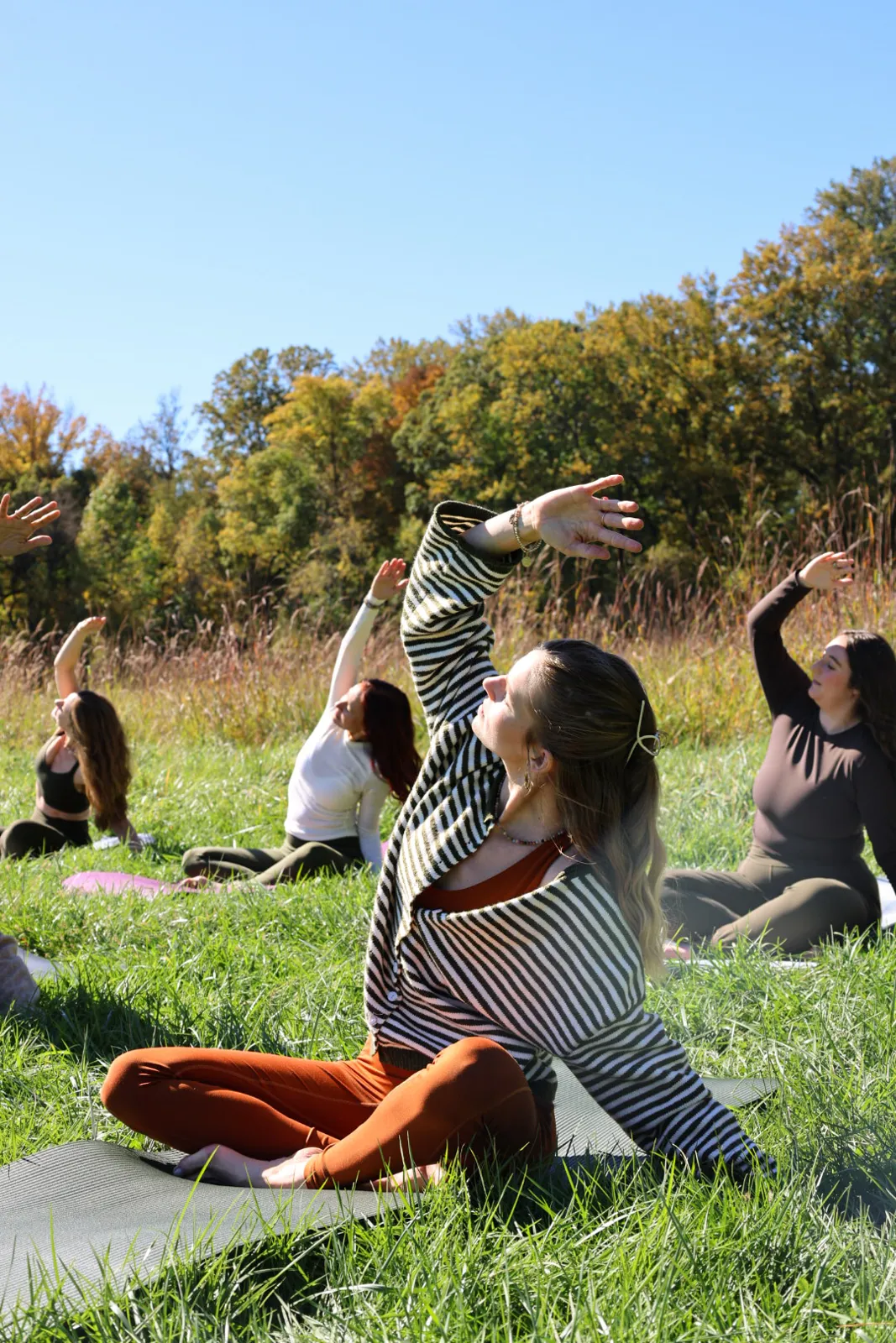 Woman in a seated twist on a mat with the group behind her