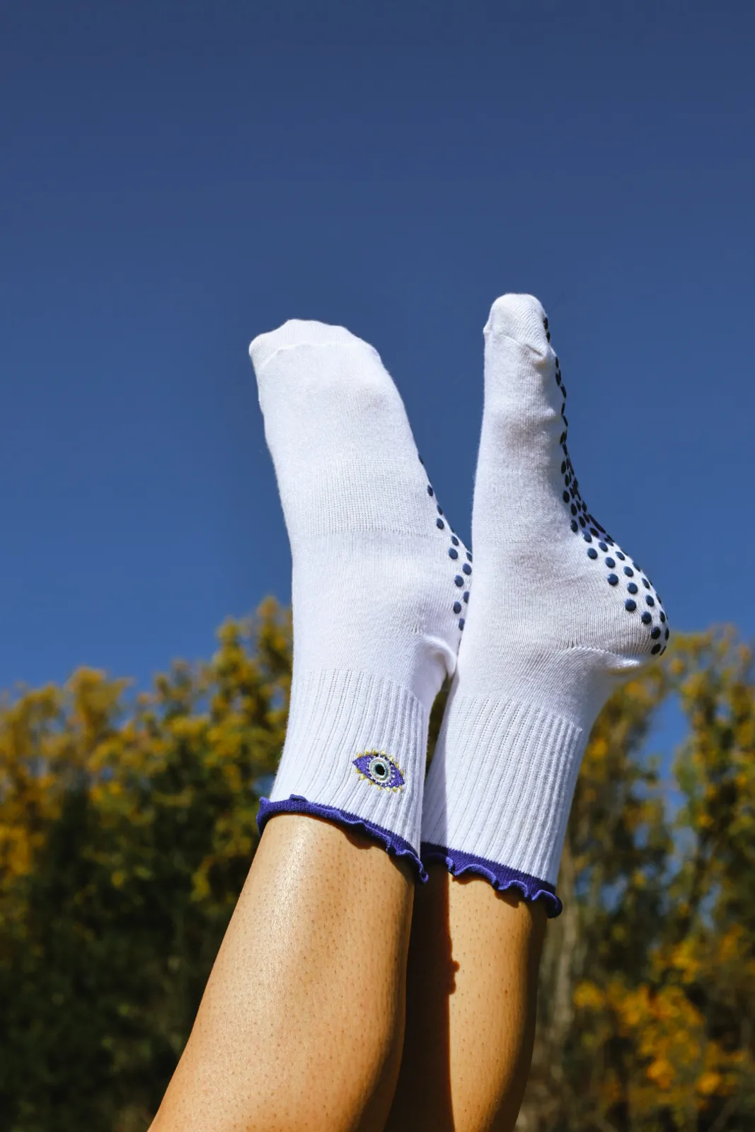 Feet in white LEV grip socks raised against a blue sky