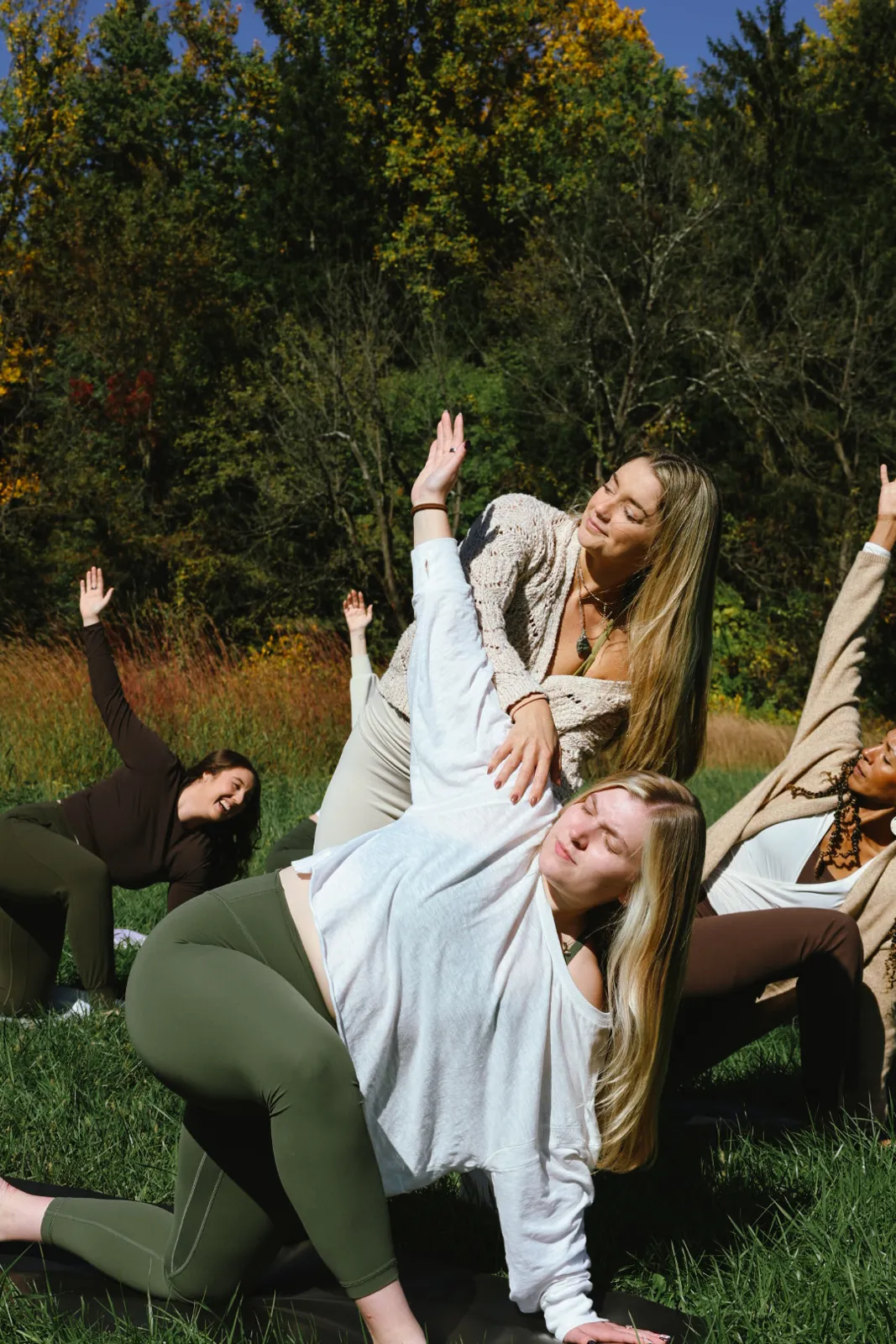 Group in a side bend together on mats in the grass